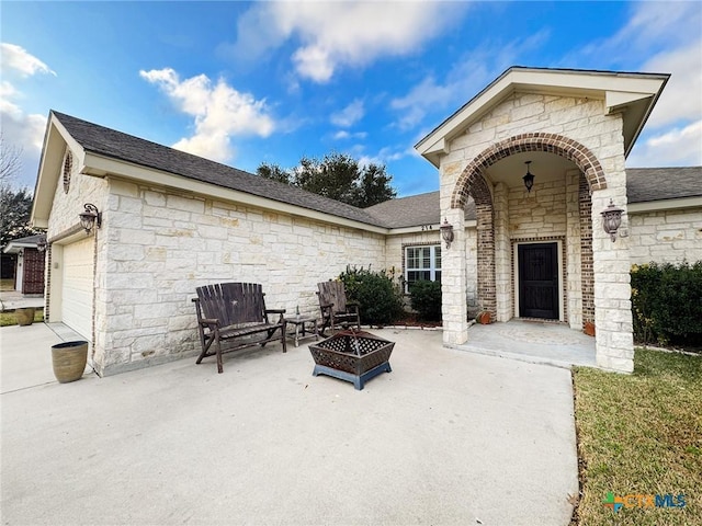 view of patio featuring a garage and a fire pit