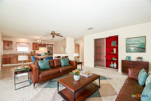 carpeted living room featuring ceiling fan with notable chandelier