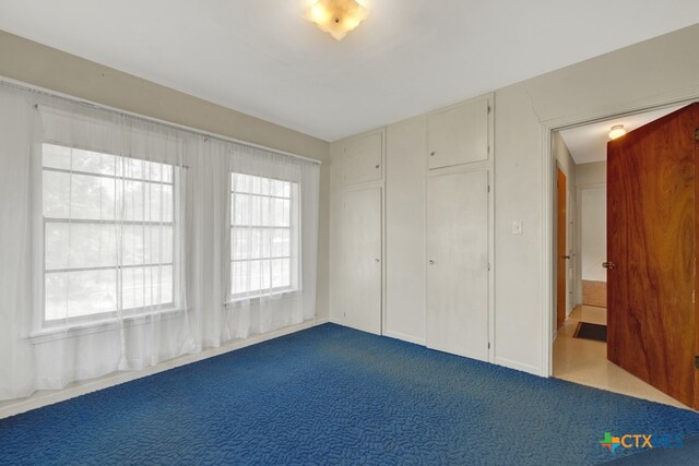 unfurnished bedroom featuring multiple windows and carpet