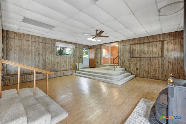 interior space with wood walls, light hardwood / wood-style flooring, a paneled ceiling, and ceiling fan