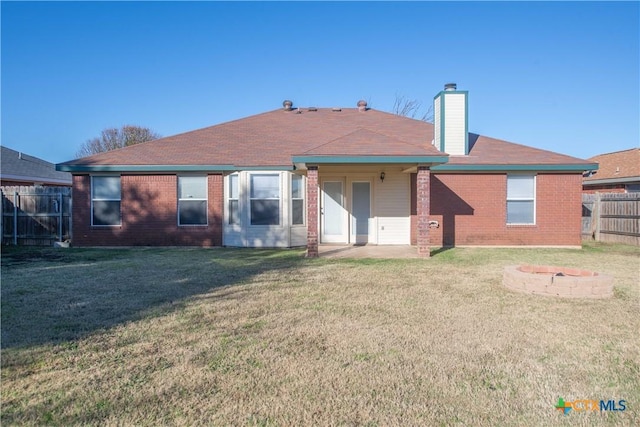 rear view of house featuring a yard and an outdoor fire pit