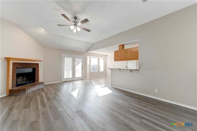 unfurnished living room with ceiling fan, a fireplace, hardwood / wood-style floors, and vaulted ceiling