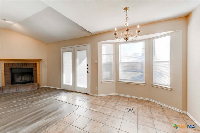 interior space with a fireplace, light tile patterned floors, a chandelier, and vaulted ceiling