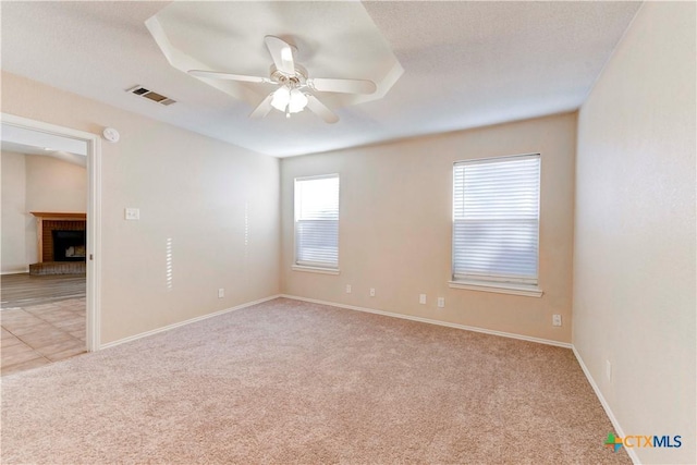 carpeted empty room featuring ceiling fan and a fireplace