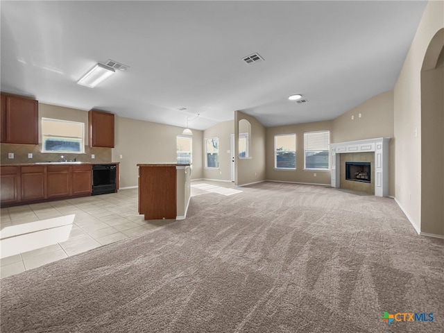 unfurnished living room featuring wine cooler, vaulted ceiling, light colored carpet, and a tile fireplace