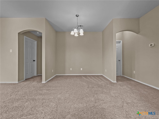 carpeted empty room featuring a notable chandelier