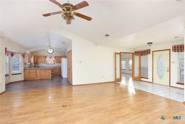 unfurnished living room with ceiling fan, vaulted ceiling, and light hardwood / wood-style floors