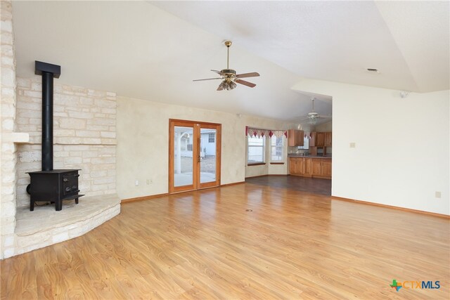 unfurnished living room featuring light wood-type flooring, vaulted ceiling, ceiling fan, and french doors