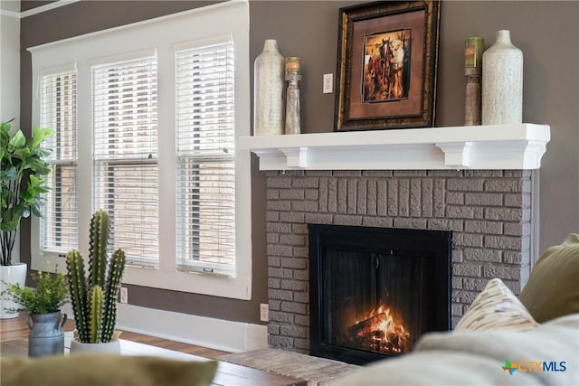 interior details with wood finished floors, baseboards, and a brick fireplace