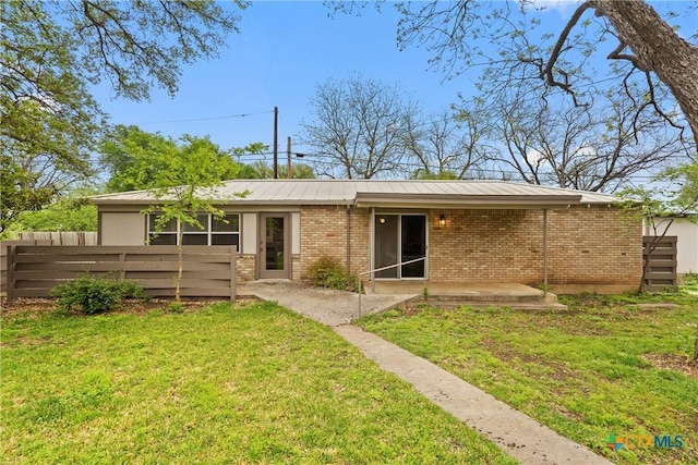 back of house with a yard, a patio area, metal roof, fence, and brick siding