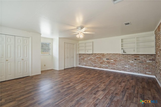 interior space with dark wood-style flooring, built in features, ceiling fan, and brick wall