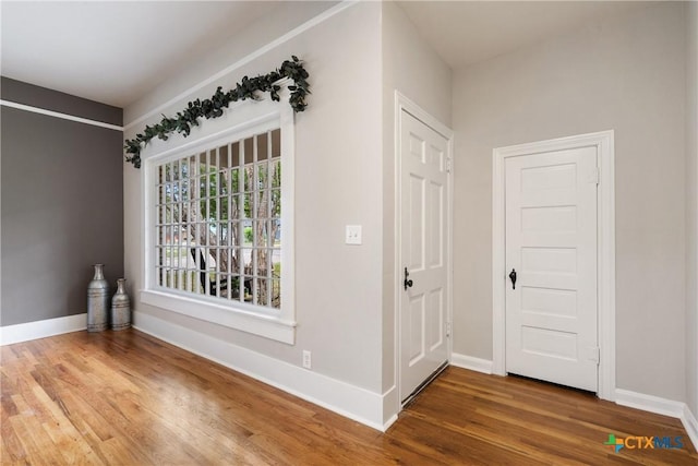 corridor with baseboards and wood finished floors