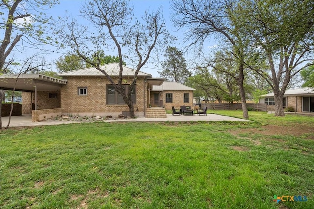 rear view of house featuring a patio area, brick siding, and a yard