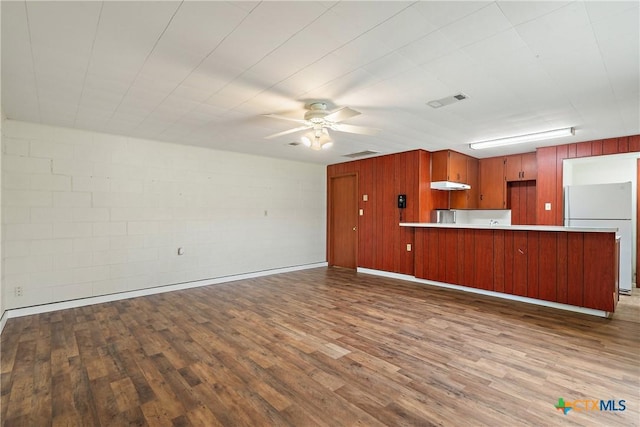 kitchen featuring visible vents, a peninsula, freestanding refrigerator, and wood finished floors