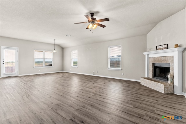 unfurnished living room with lofted ceiling, dark wood-type flooring, a textured ceiling, ceiling fan, and a fireplace