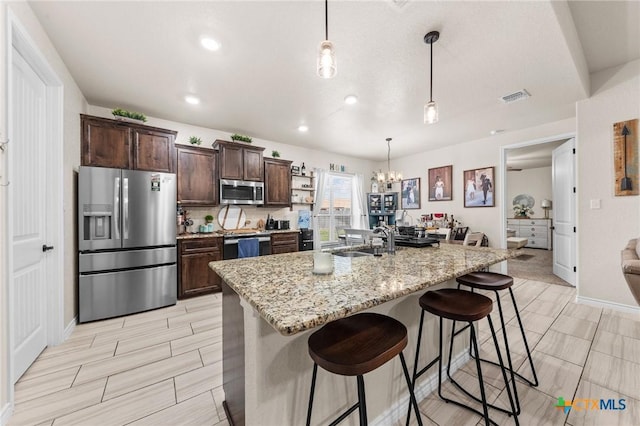 kitchen with dark brown cabinets, a sink, stainless steel appliances, a notable chandelier, and visible vents