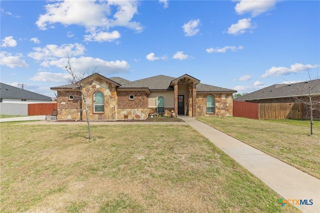 ranch-style house featuring stone siding, a front lawn, and fence