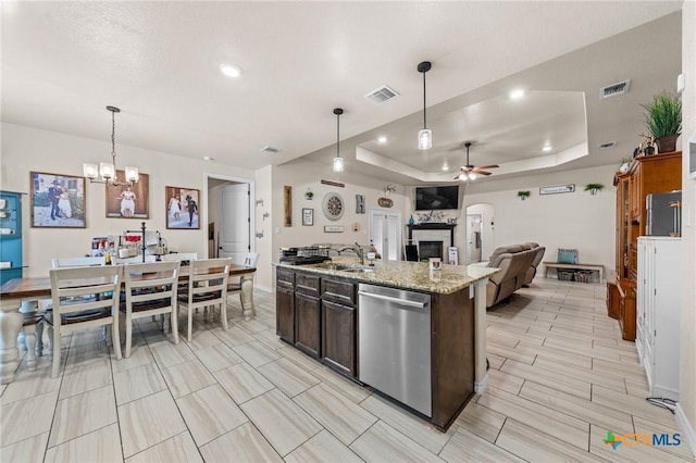 kitchen with ceiling fan with notable chandelier, dishwasher, visible vents, and a tray ceiling