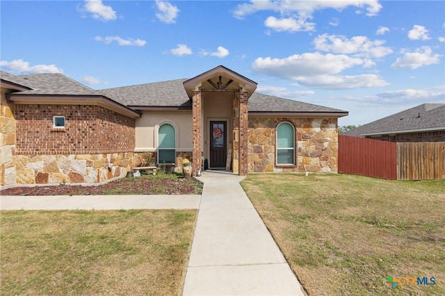 single story home with fence, stucco siding, stone siding, roof with shingles, and a front yard