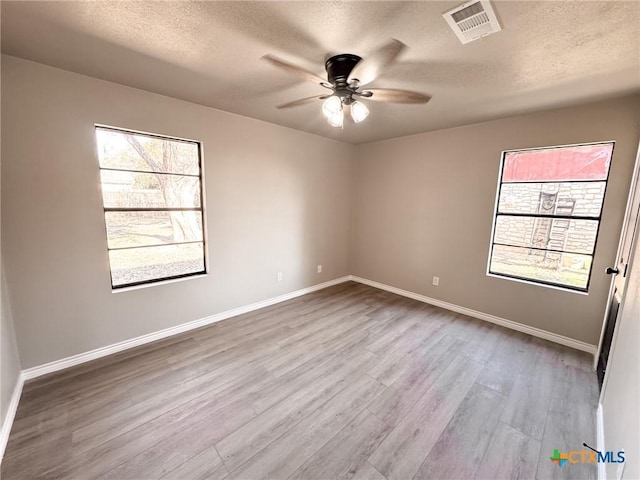 empty room featuring ceiling fan, a textured ceiling, and light hardwood / wood-style floors