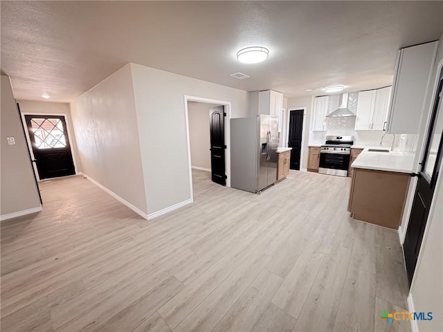 kitchen featuring wall chimney exhaust hood, sink, appliances with stainless steel finishes, light hardwood / wood-style floors, and white cabinets