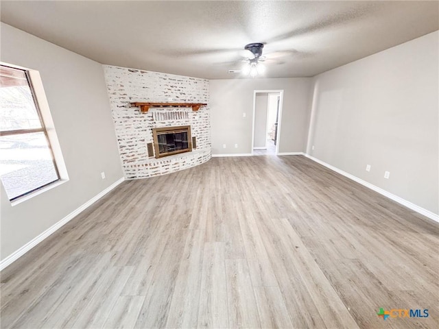 unfurnished living room with a textured ceiling, a fireplace, light hardwood / wood-style floors, and ceiling fan