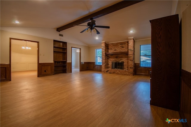 unfurnished living room with vaulted ceiling with beams, ceiling fan with notable chandelier, a brick fireplace, and light hardwood / wood-style flooring