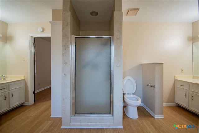 bathroom featuring toilet, an enclosed shower, vanity, and wood-type flooring