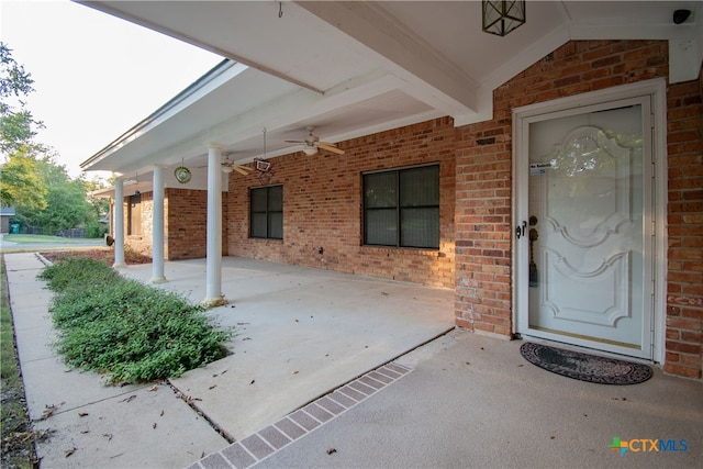 view of exterior entry with ceiling fan and a patio area