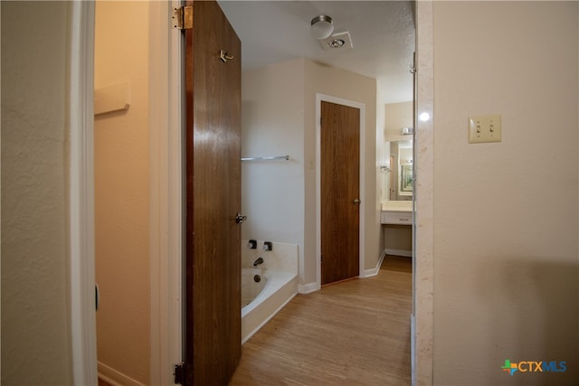 hallway with light wood-type flooring and a textured ceiling