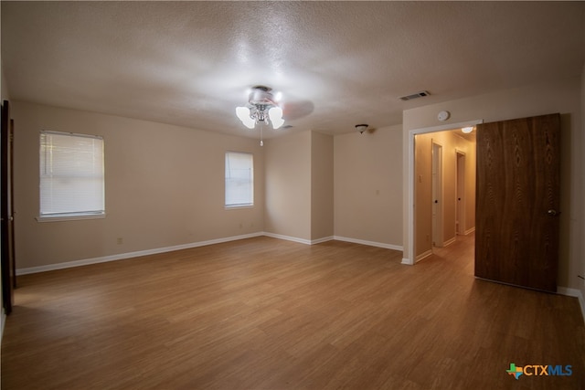 empty room featuring ceiling fan, a textured ceiling, and light wood-type flooring