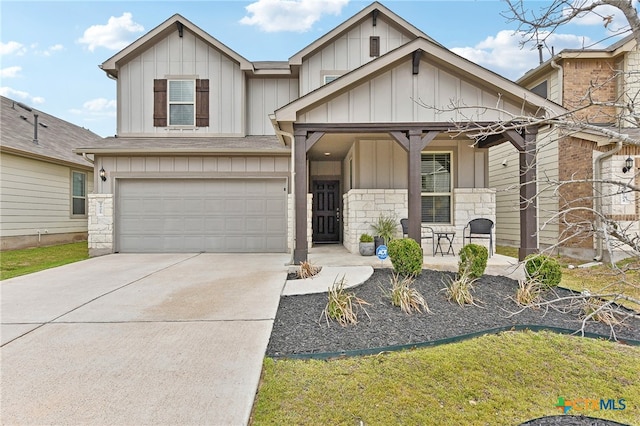 view of front of home with covered porch, an attached garage, board and batten siding, stone siding, and driveway