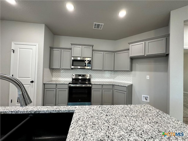 3110 Gryffindor Ln, Killeen, TX 76549 - kitchen featuring stainless steel appliances, gray cabinetry, light stone countertops, and decorative backsplash