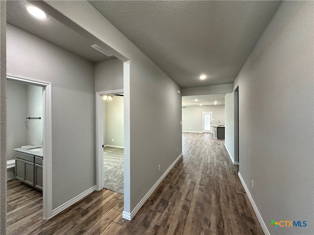 hall featuring a textured ceiling and dark hardwood / wood-style floors