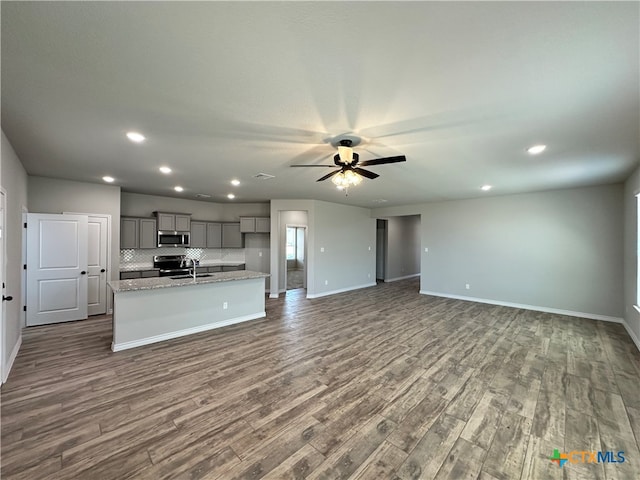 kitchen featuring stainless steel appliances, sink, a kitchen island with sink, gray cabinetry, and dark hardwood / wood-style flooring