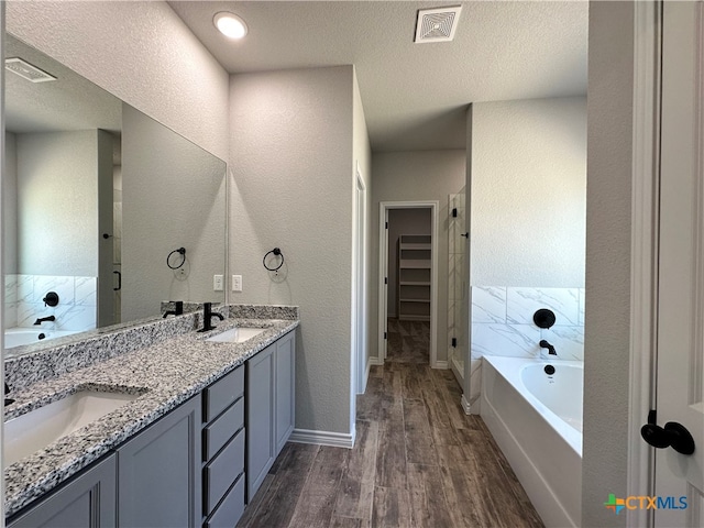 bathroom featuring a bathing tub, hardwood / wood-style floors, vanity, and a textured ceiling