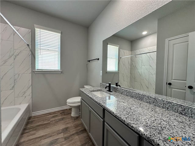 full bathroom with wood-type flooring, tiled shower / bath combo, toilet, and vanity