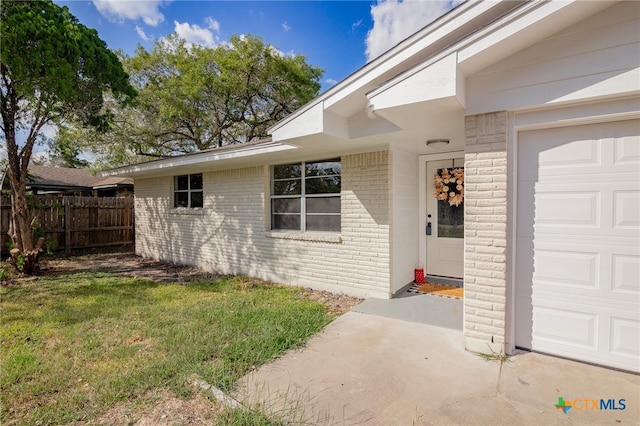 property entrance with a lawn and a garage