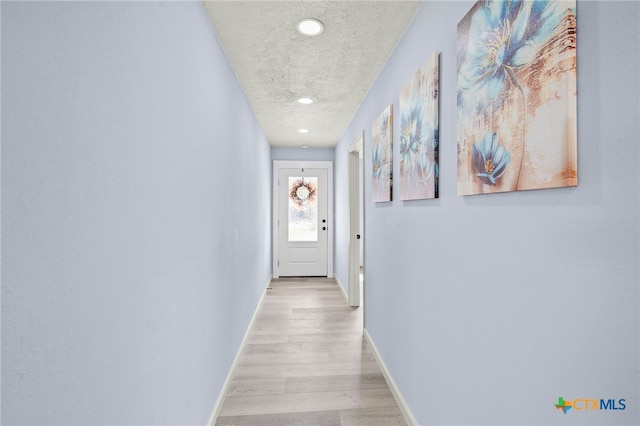 hallway featuring light hardwood / wood-style floors and a textured ceiling