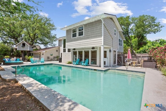 rear view of property featuring an outdoor hangout area, a fenced in pool, a patio, and fence