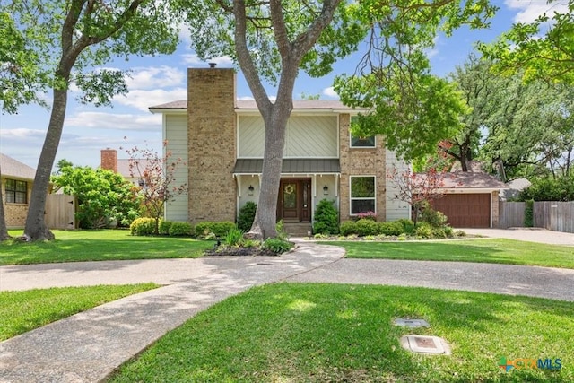 view of front of home with a front lawn, driveway, a chimney, fence, and an attached garage