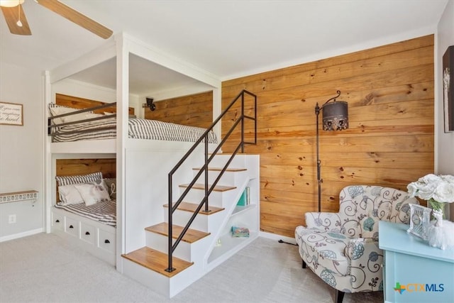 bedroom featuring wooden walls, carpet floors, and baseboards
