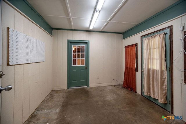 entryway featuring wood walls and unfinished concrete flooring