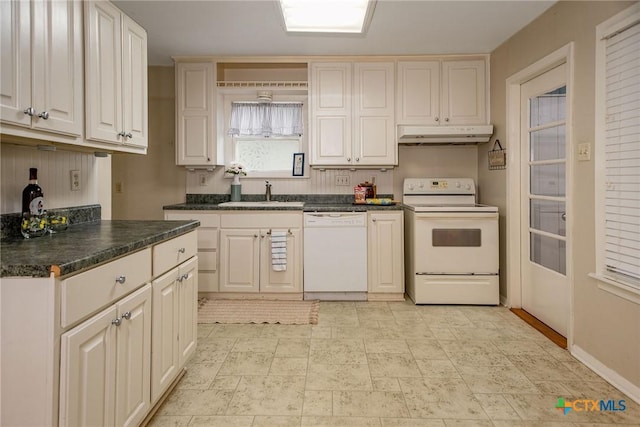 kitchen with white appliances, dark countertops, under cabinet range hood, and a sink