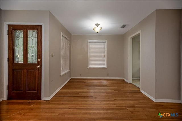 foyer entrance featuring baseboards, wood finished floors, and visible vents