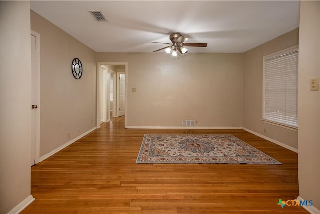 empty room with visible vents, baseboards, ceiling fan, and wood finished floors