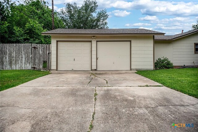 garage featuring fence and driveway
