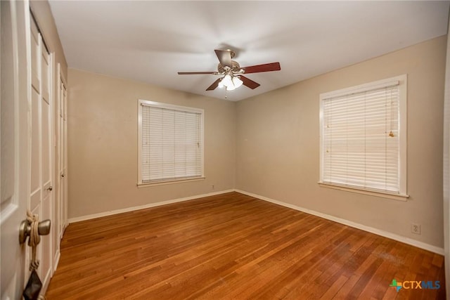 unfurnished bedroom with baseboards, ceiling fan, wood finished floors, and a closet