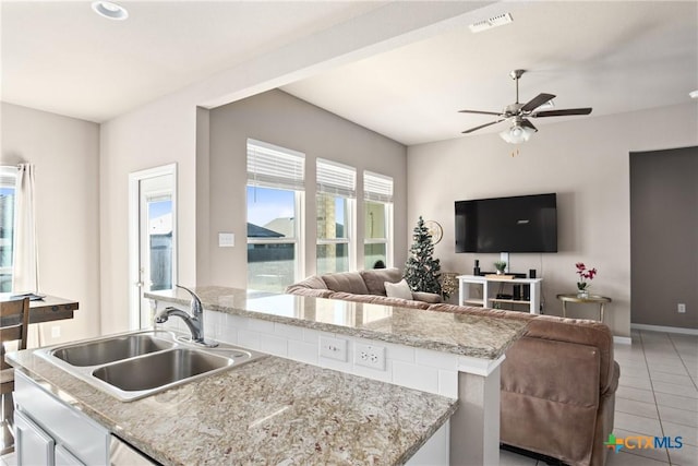 kitchen with light stone countertops, ceiling fan, sink, white cabinetry, and light tile patterned flooring