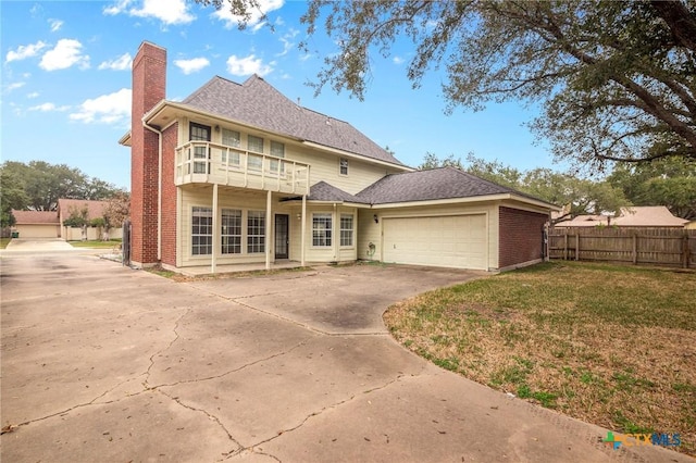 back of house with a garage, a balcony, and a lawn